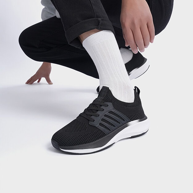 Ben med svarte joggesko med hvite detaljer